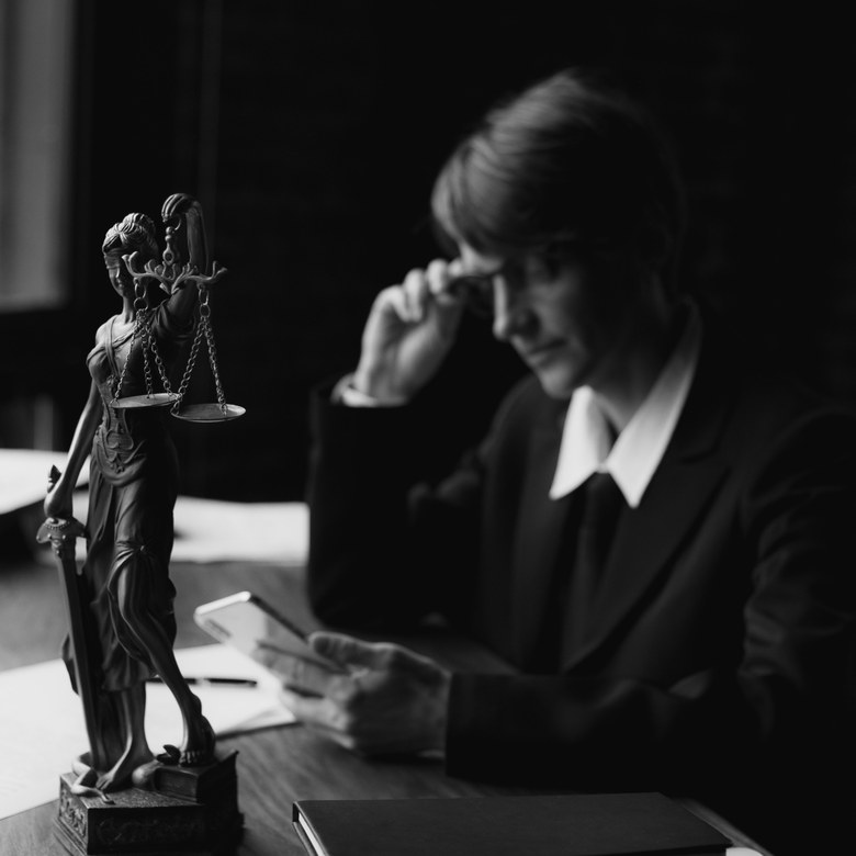 A statue of Lady Justice on a desk while an attorney reviews a case file